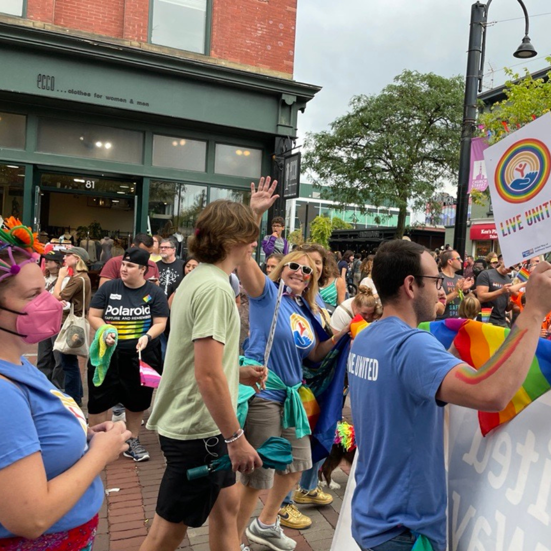 United Way staff marching down Church Street during the pride parade as bystanders look on.