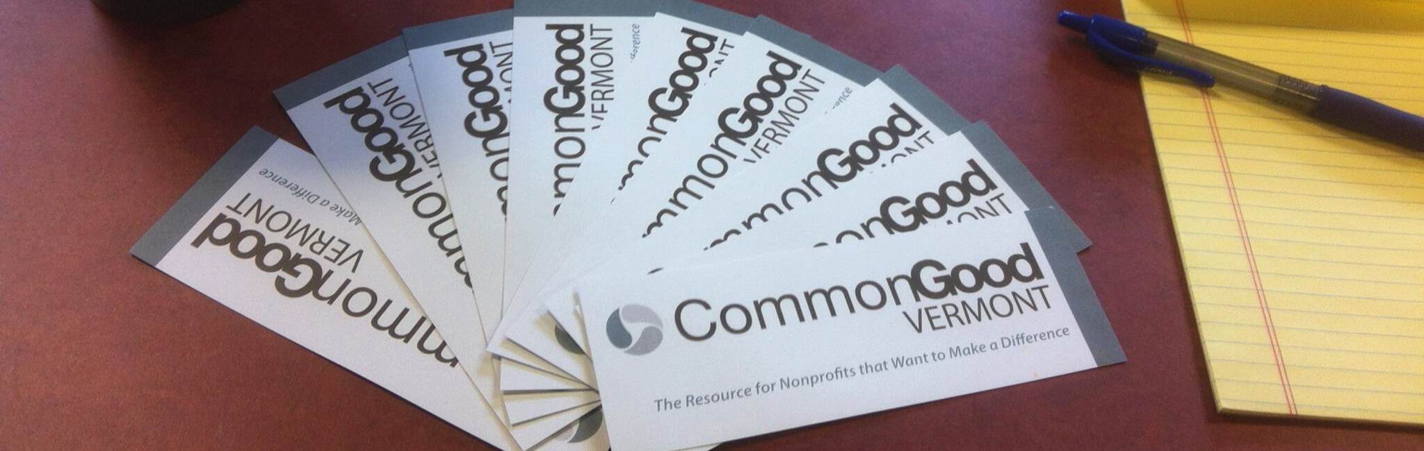 Business cards that say "Common Good Vermont: The resource for nonprofits that want to make a difference are splayed out on a desk next to a notepad.