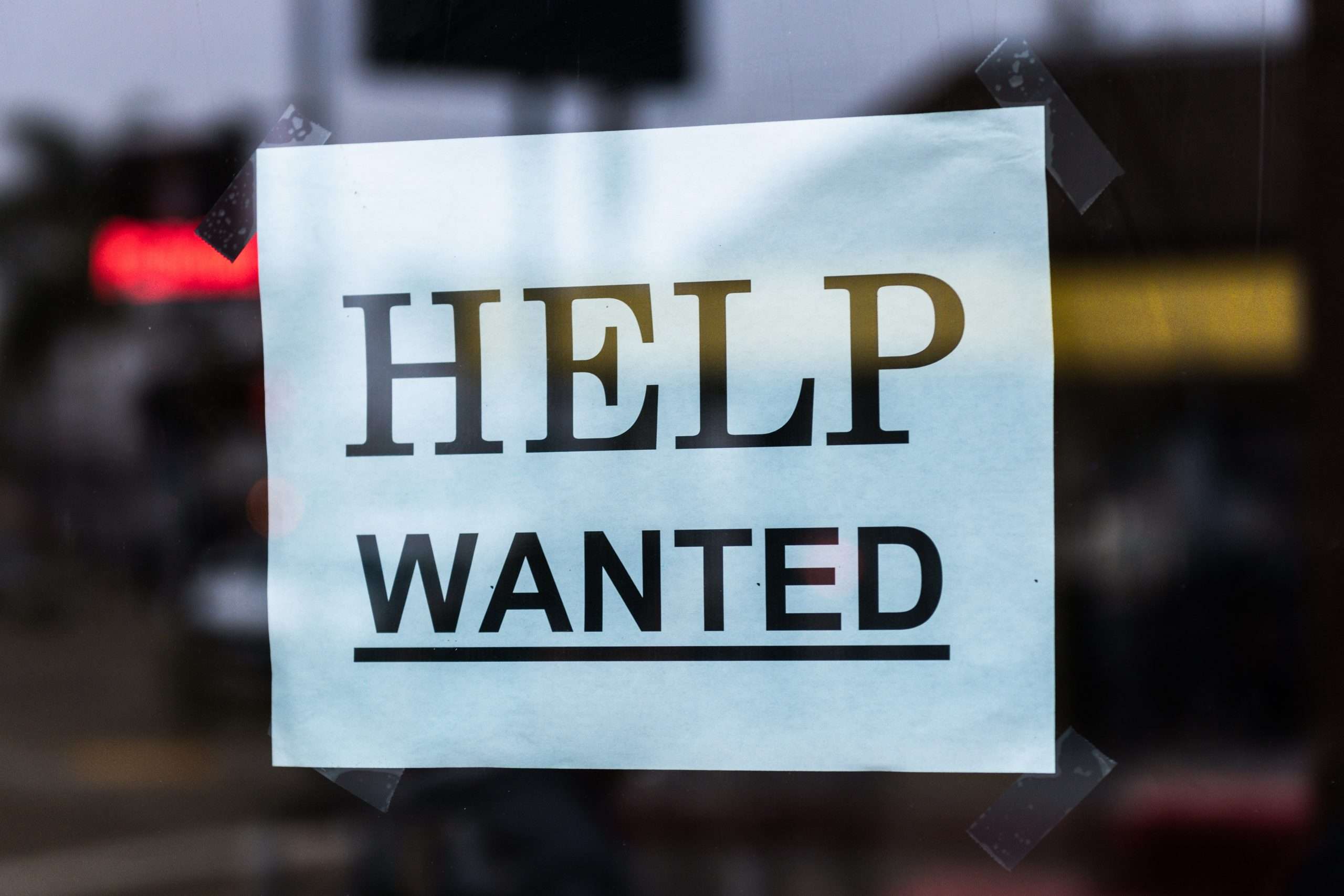 A "Help Wanted" sign posted in a window.