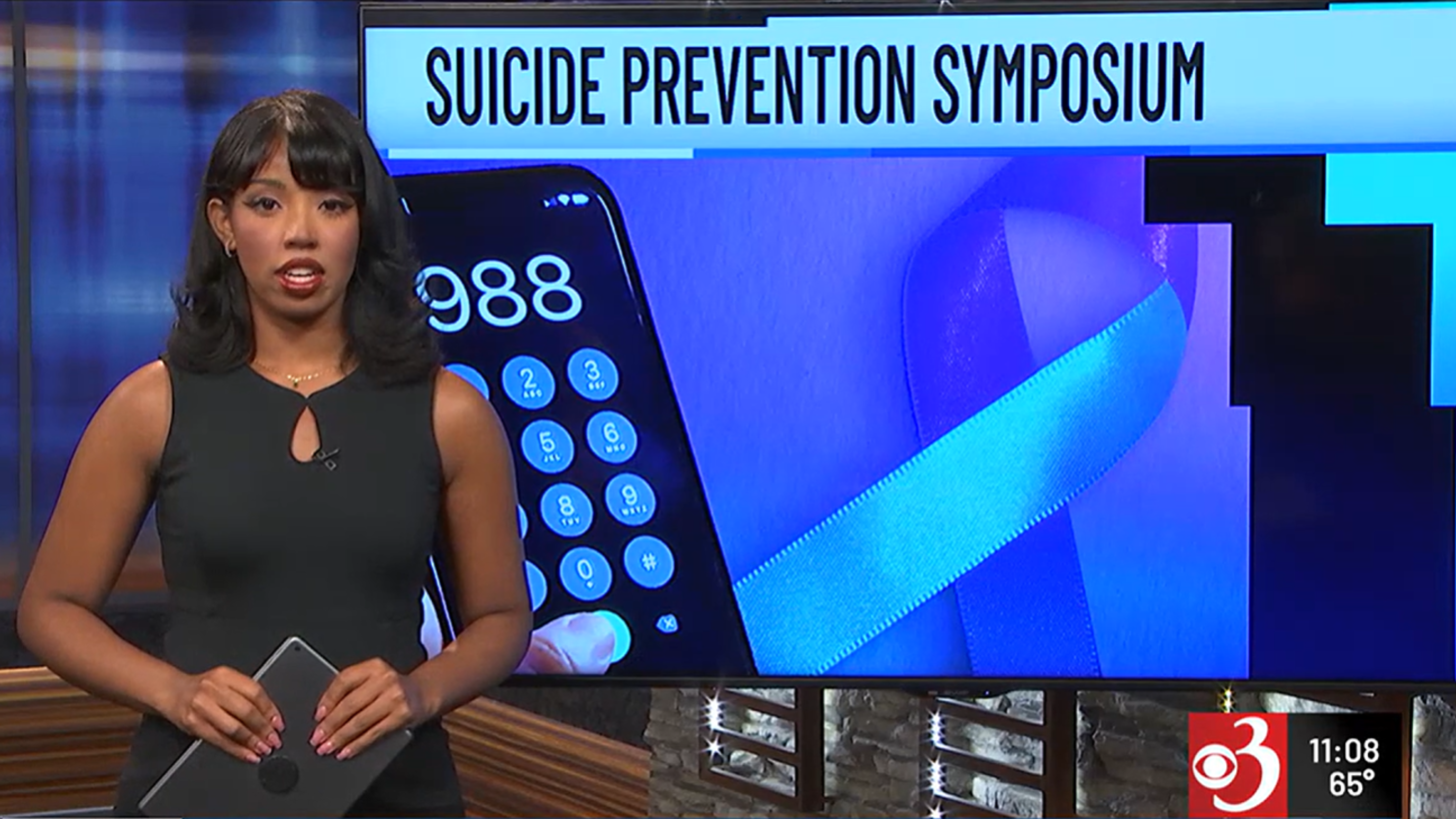 WCAX news reporter in front of a headline reading Suicide Prevention Symposium