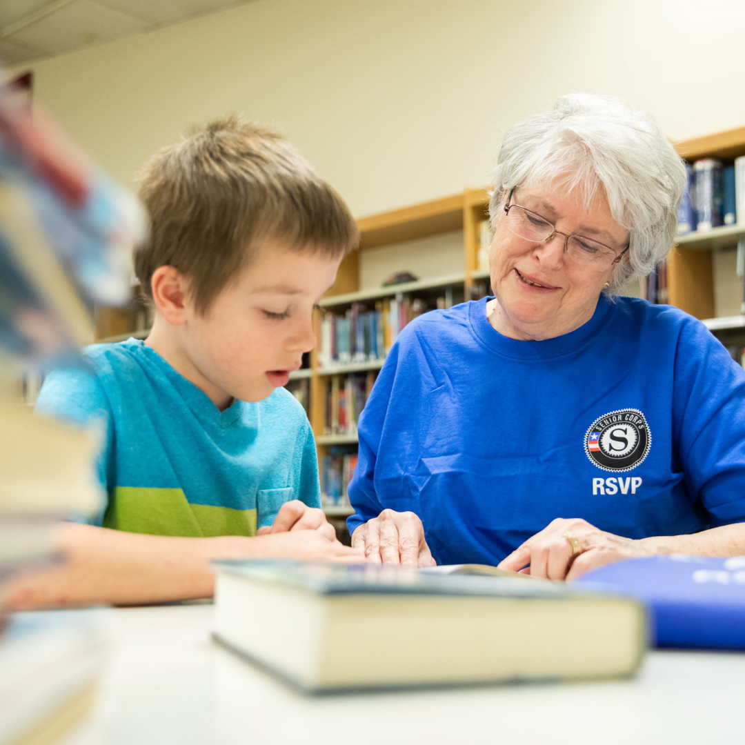An AmeriCorps Seniors RSVP volunteer reads with a child