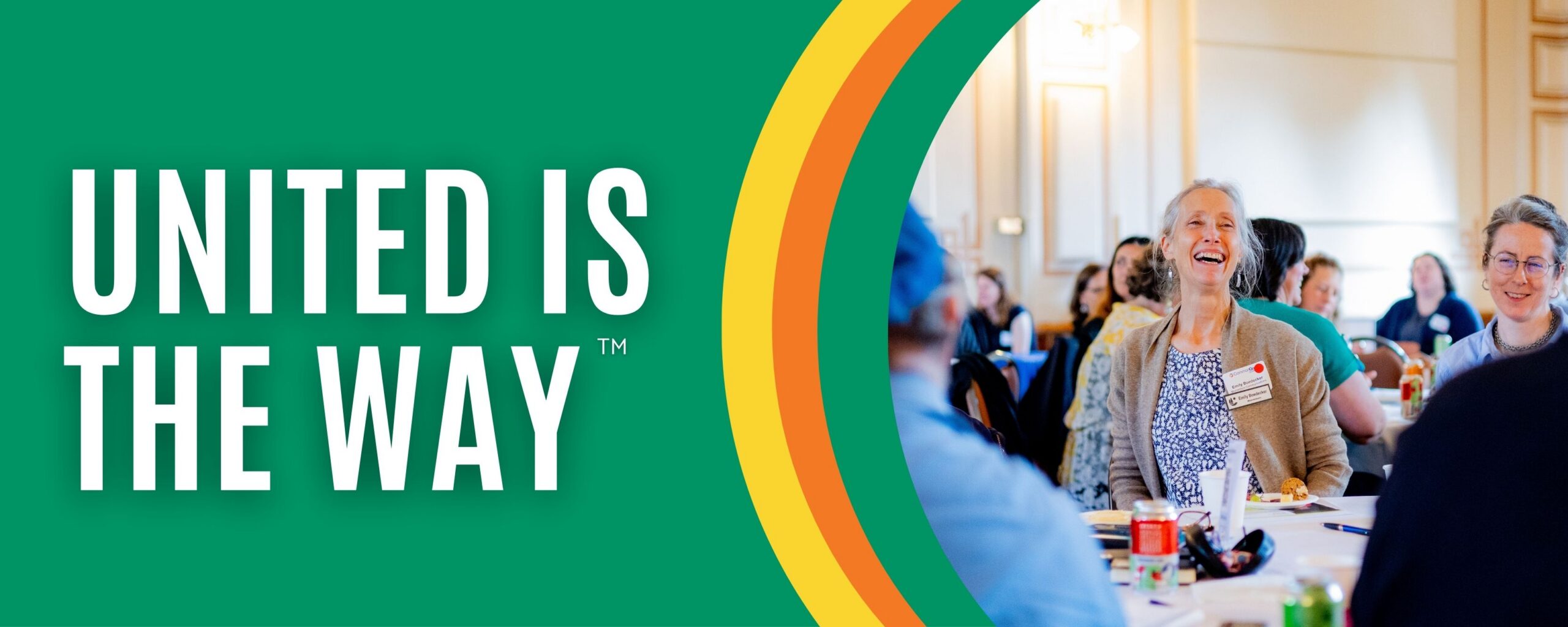 A green banner with the words "United is the way" and a photo of a woman at a busy table laughing with peers